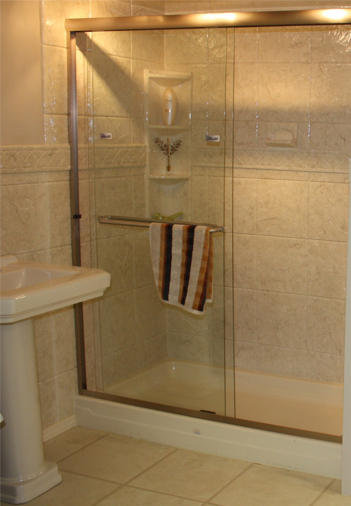 A bathroom featuring a shower and a sink, with modern fixtures and neutral-colored tiles.