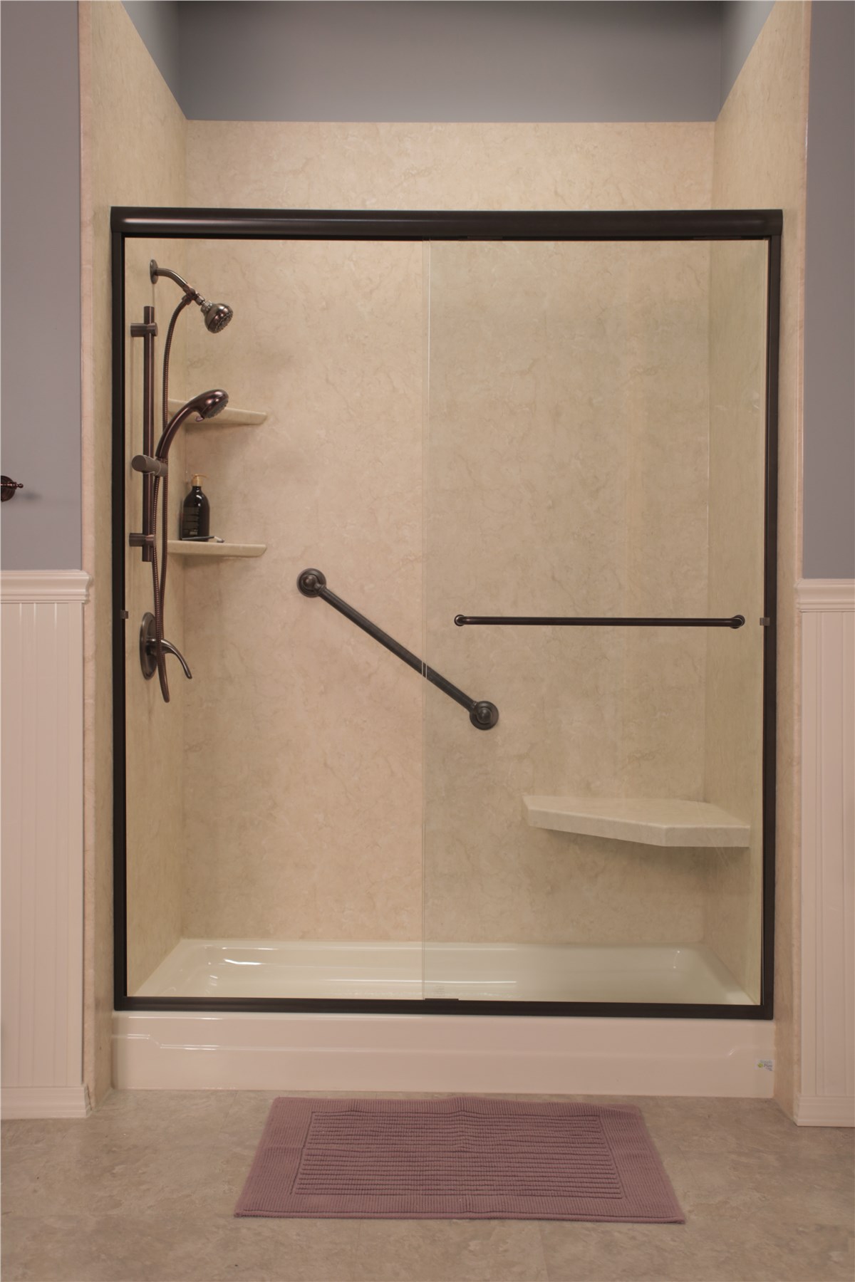 A modern shower featuring a glass door and a black handrail for accessibility.