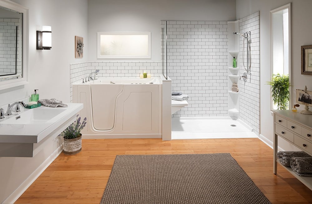 A spacious bathroom with a walk-in bathtub, subway-tiled shower, double vanity, and decorative plants.