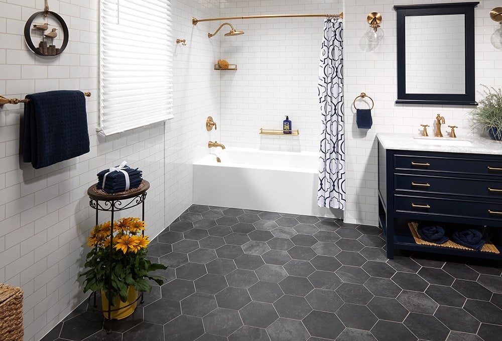A stylish bathroom with a navy vanity, gold fixtures, subway-tiled bathtub, and patterned shower curtain.